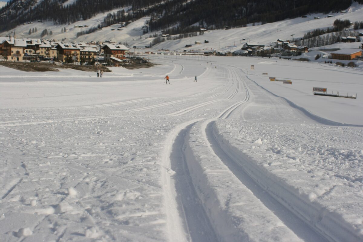 Groomed cross-country tracks across the snow, with village houses at the edge of the valley floor