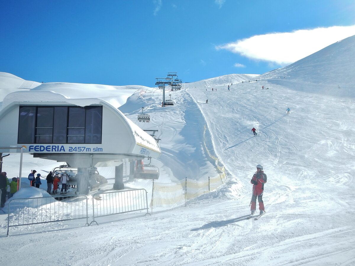 The Federia chairlift station in the snow, with a skier on the piste beside it