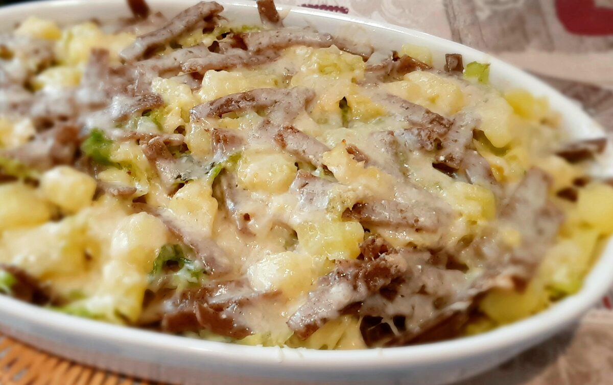 A baking dish of pizzoccheri, dark buckwheat ribbon pasta baked with potato, cabbage and melted cheese