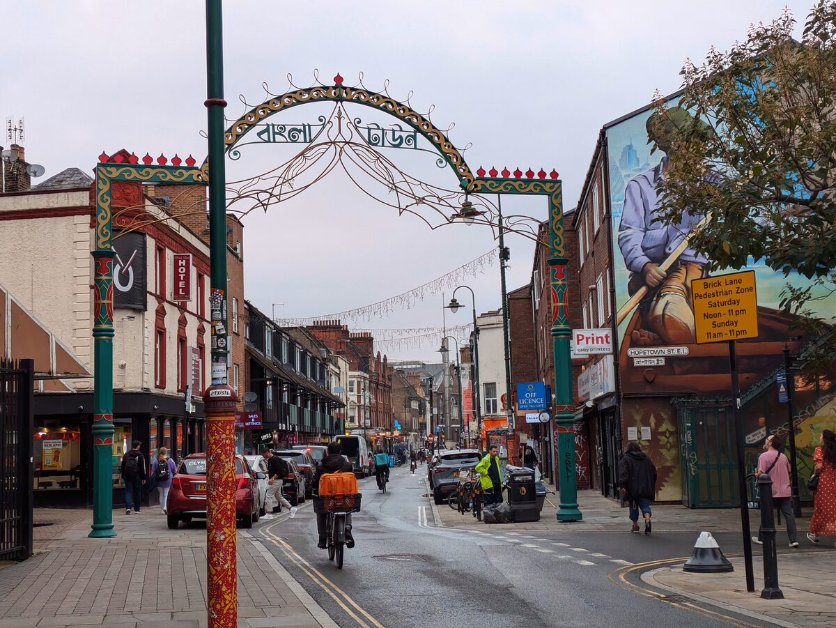 Brick Lane in East London, with an arch over the street, shopfronts and painted walls