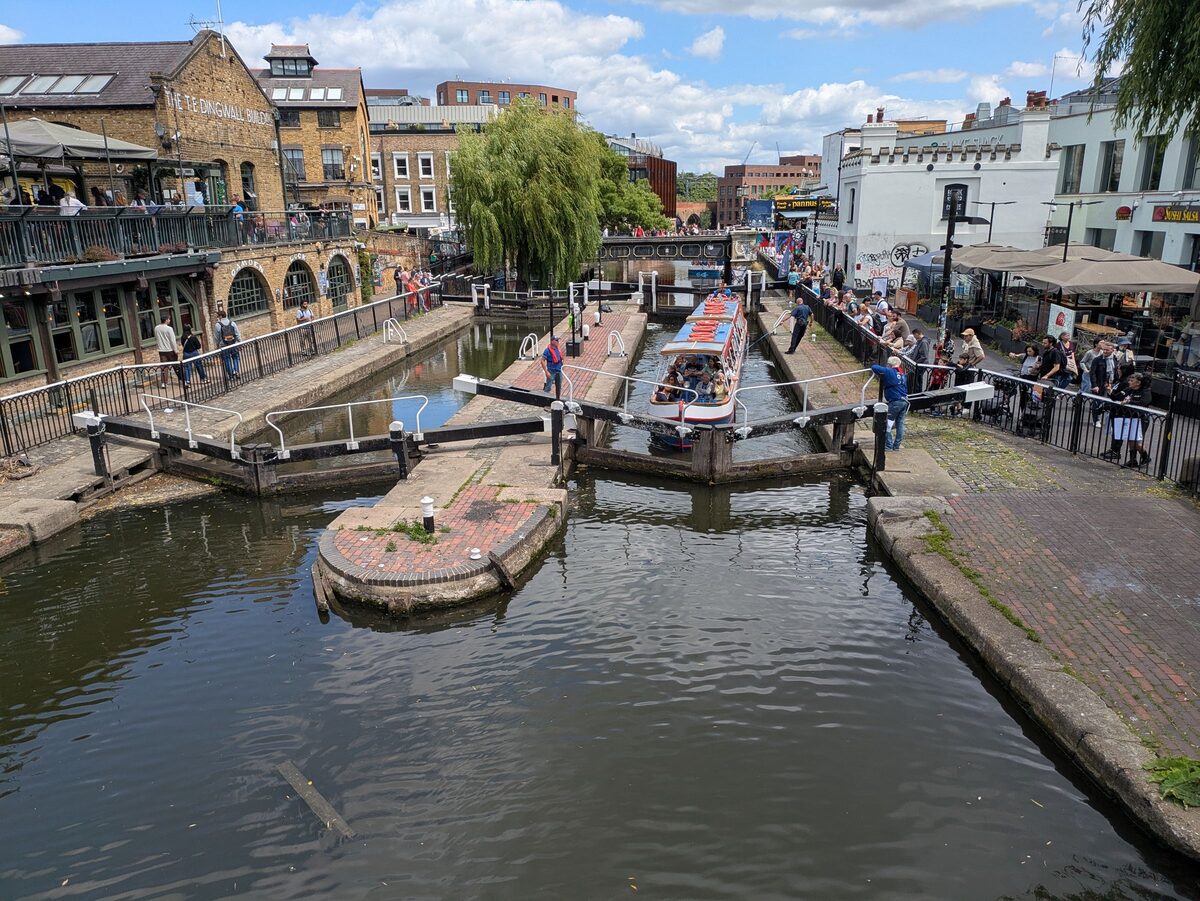 Narrowboats moored by Camden Lock on Regent's Canal, with market buildings behind