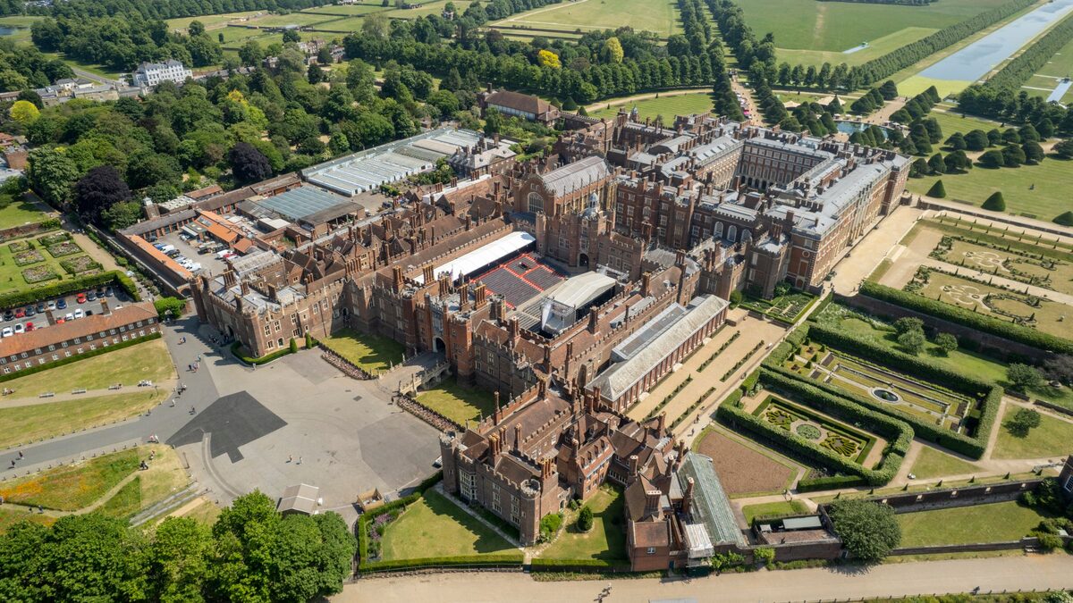 Aerial view of Hampton Court Palace, its red-brick Tudor courtyards and formal gardens beside the Thames