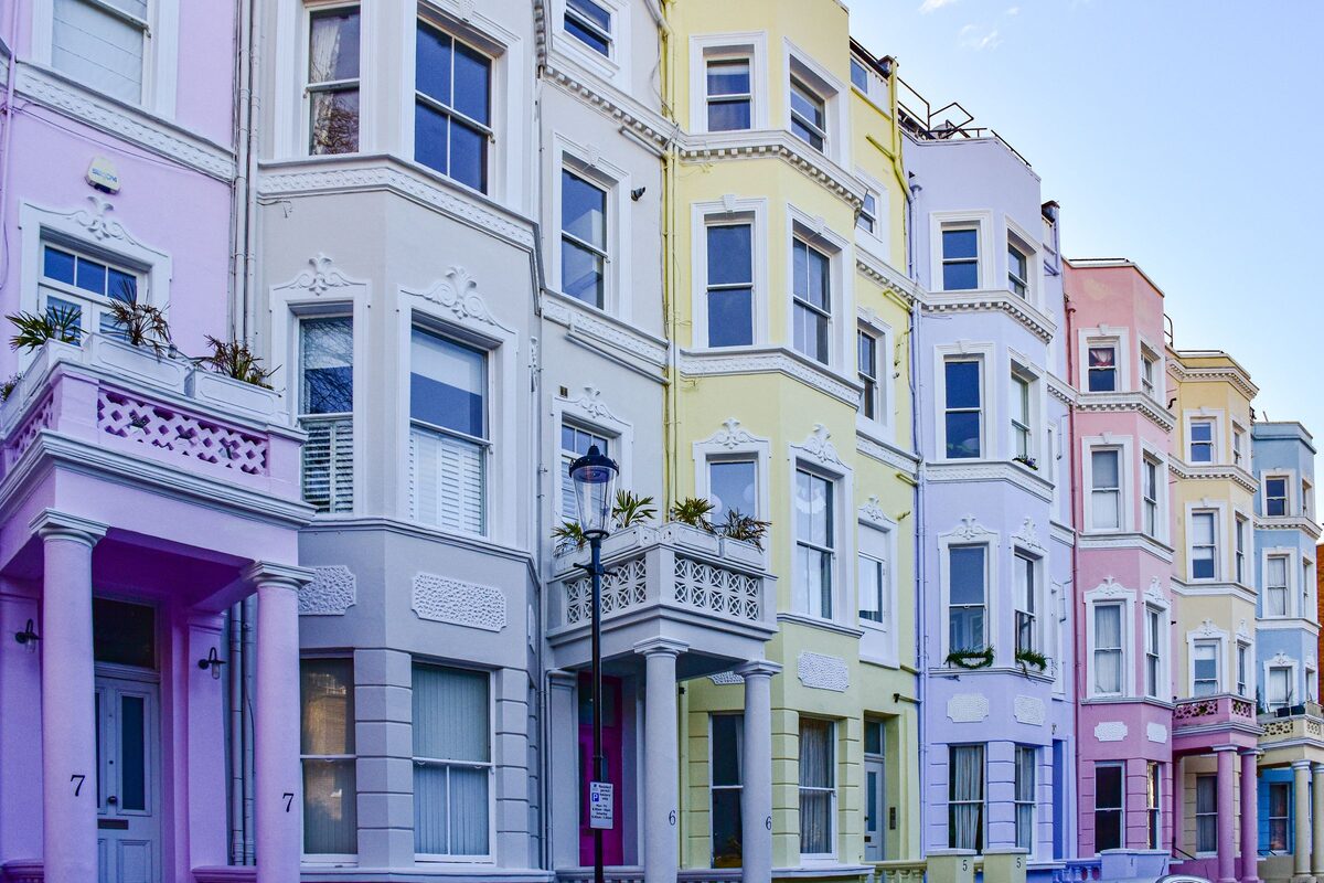 A row of houses painted in pastel pink, blue and yellow on a street in Notting Hill