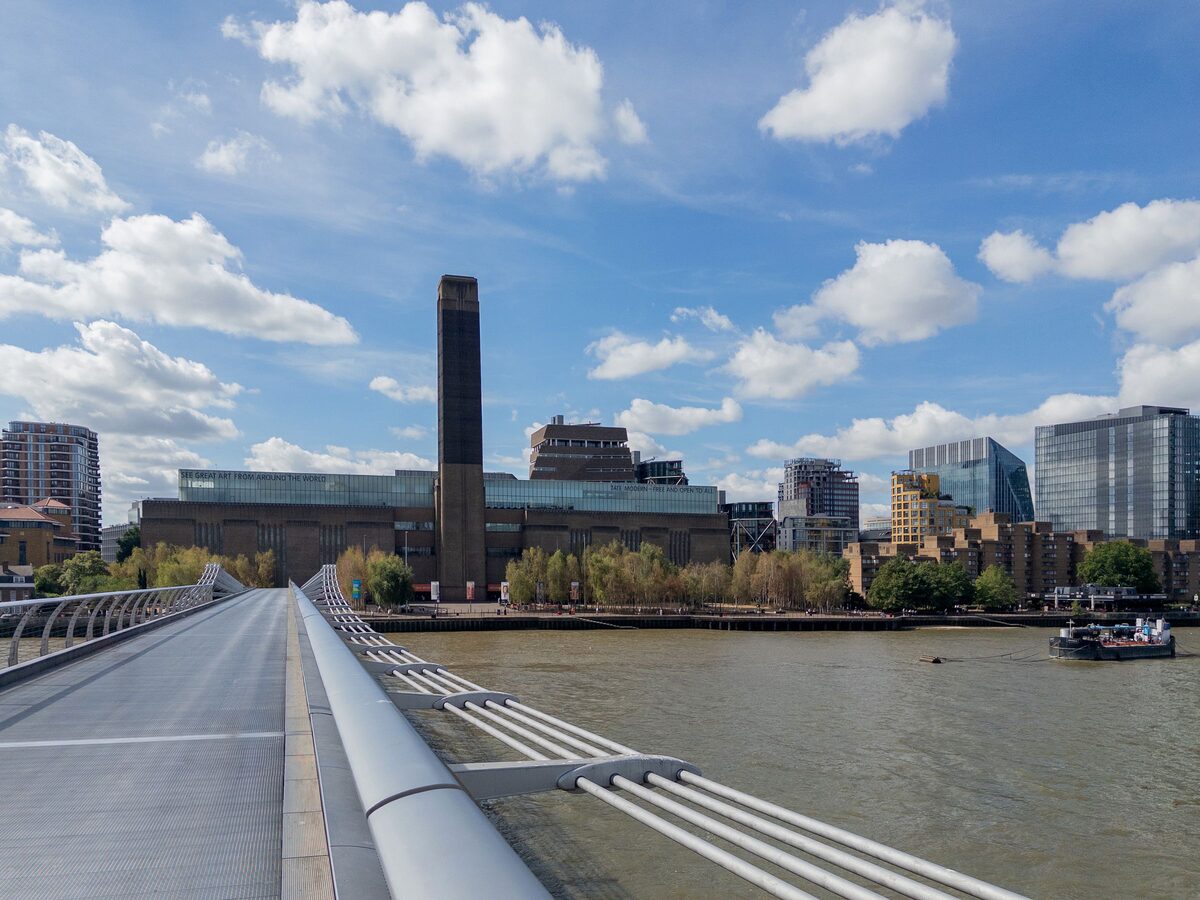 Tate Modern, a former brick power station with a tall chimney, beside the Millennium Bridge over the Thames
