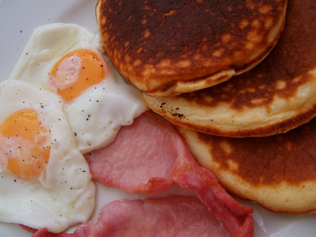 An American breakfast plate of pancakes, fried eggs and bacon