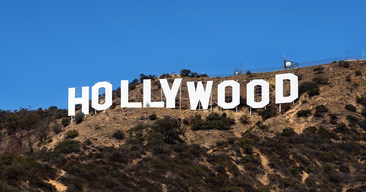 The white Hollywood Sign letters on the dry brown hillside of Mount Lee under a clear blue sky