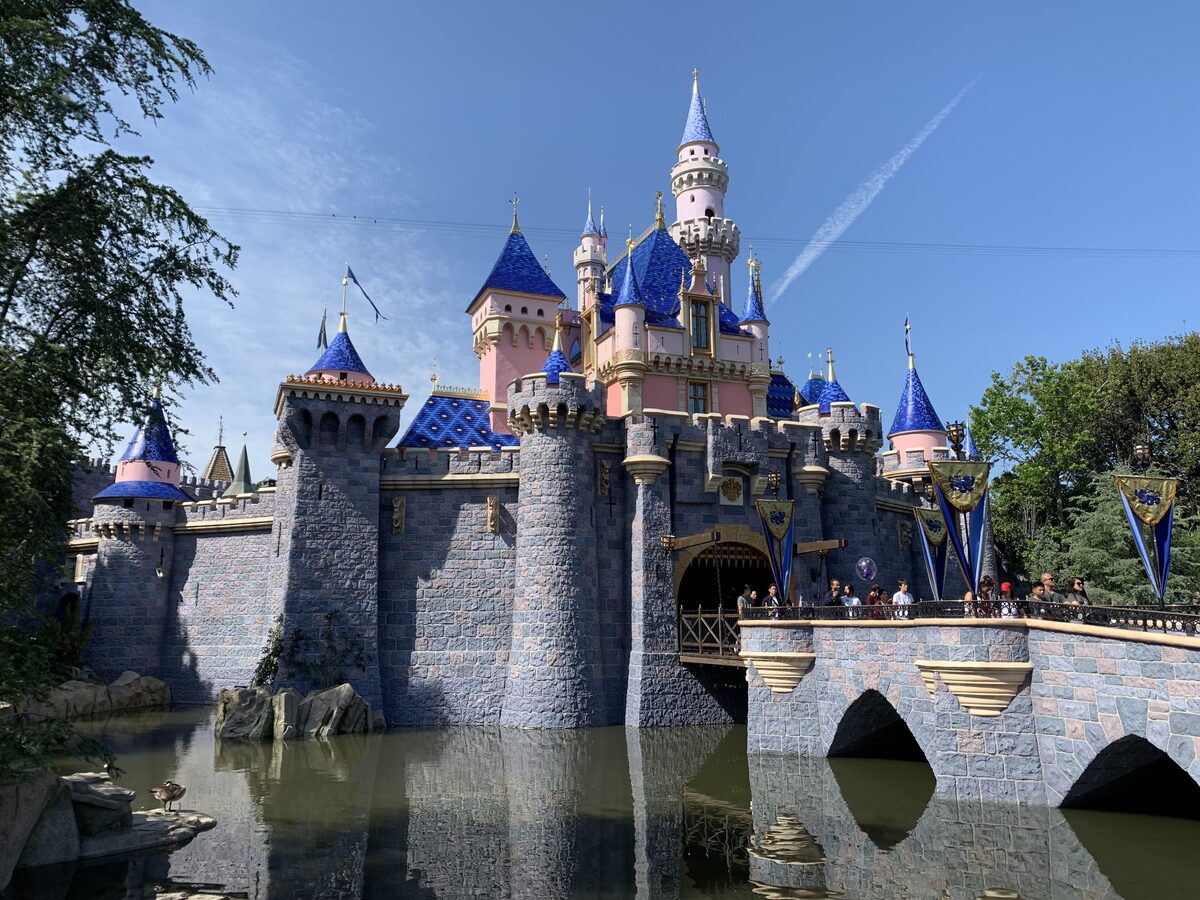 Sleeping Beauty Castle at Disneyland with its blue turrets reflected in the moat under a clear sky