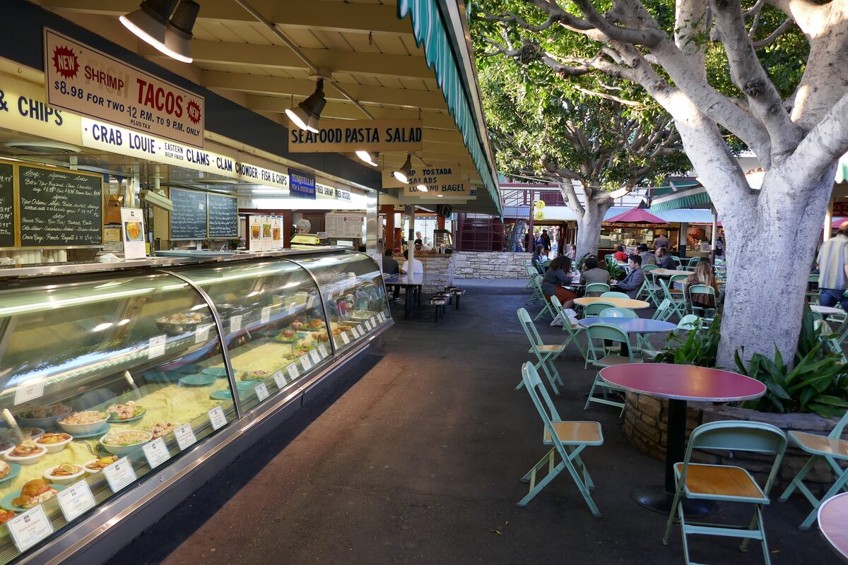 A deli counter of prepared salads and a shaded patio with café tables at the Original Farmers Market