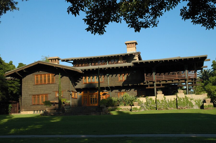 The Gamble House, a dark shingled Arts and Crafts house with wide eaves and wooden beams behind a lawn