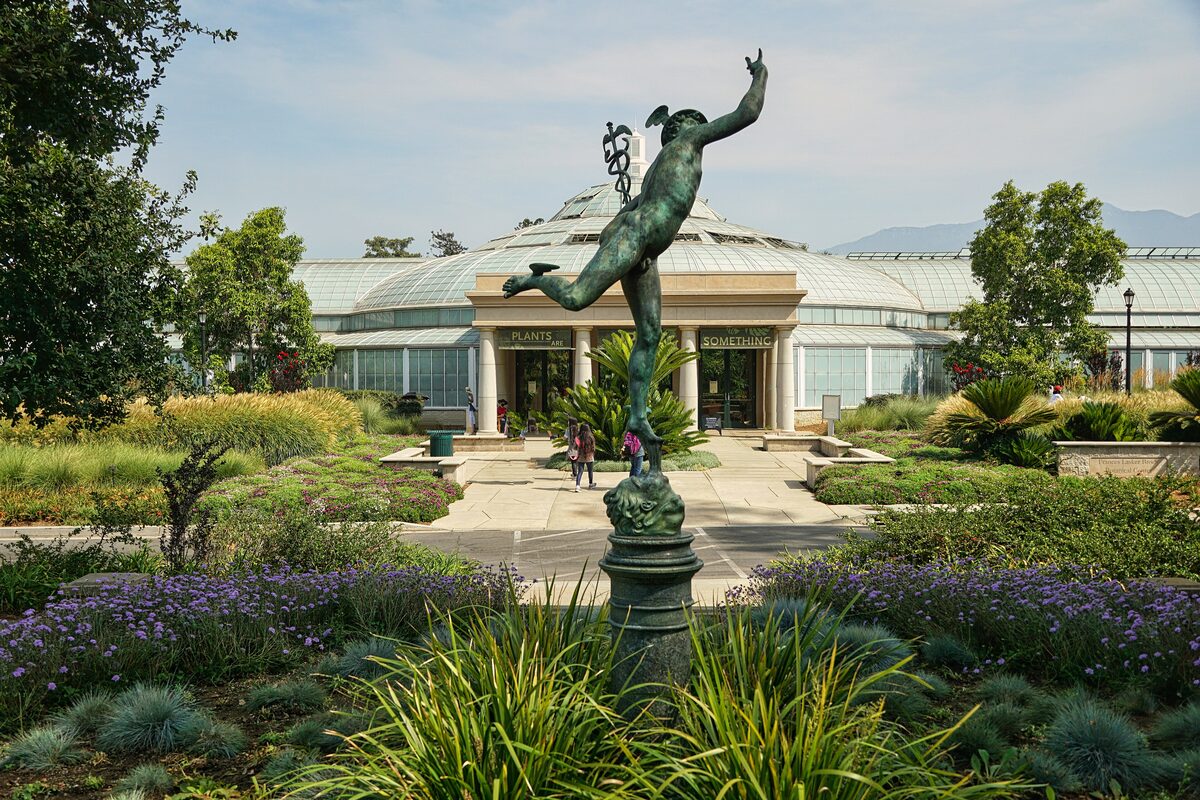 The Huntington botanical gardens with a bronze Mercury statue in front of the glass conservatory