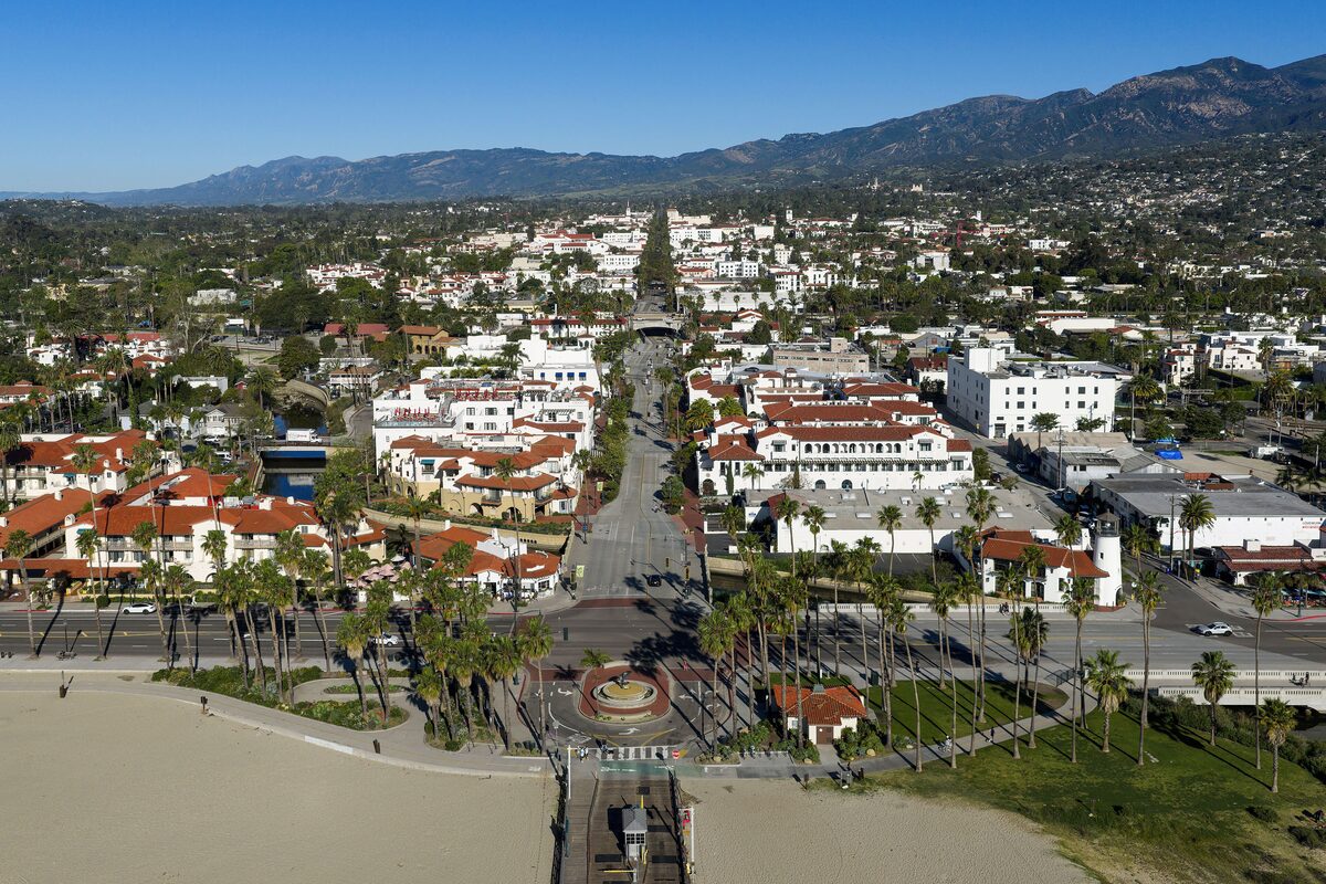 Aerial view up State Street from the Santa Barbara beach and pier, with red tile roofs and the mountains behind