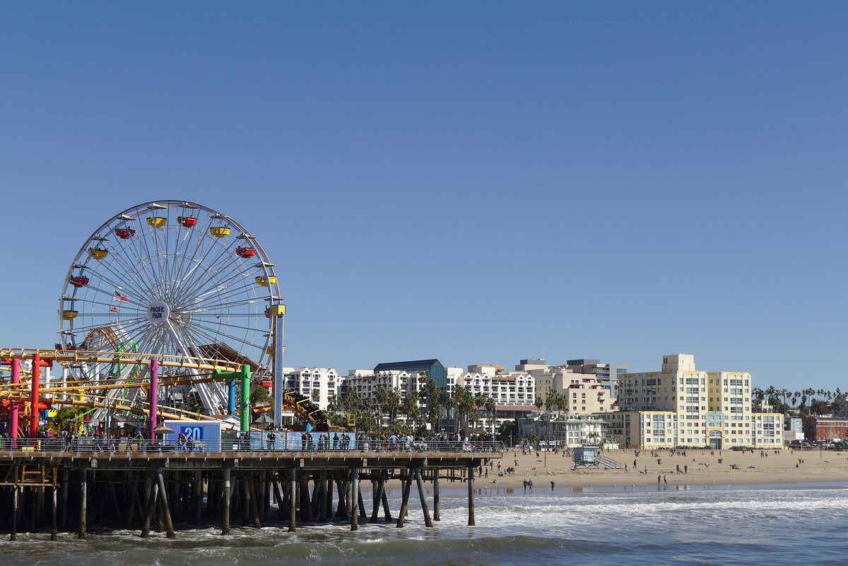 The Ferris wheel and rides of Pacific Park on Santa Monica Pier, with the beach and the city behind