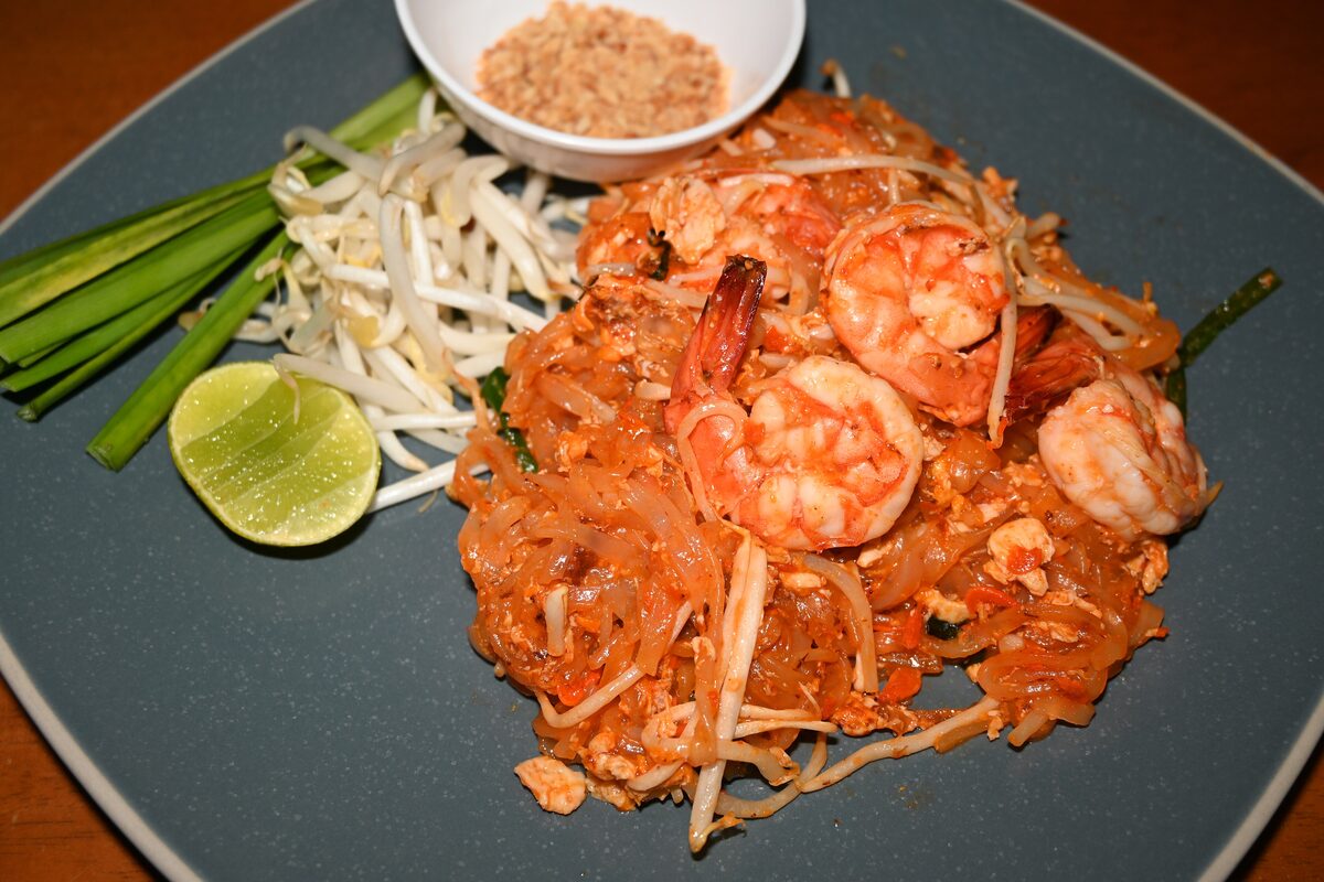 A plate of shrimp pad Thai with bean sprouts, lime and crushed peanuts