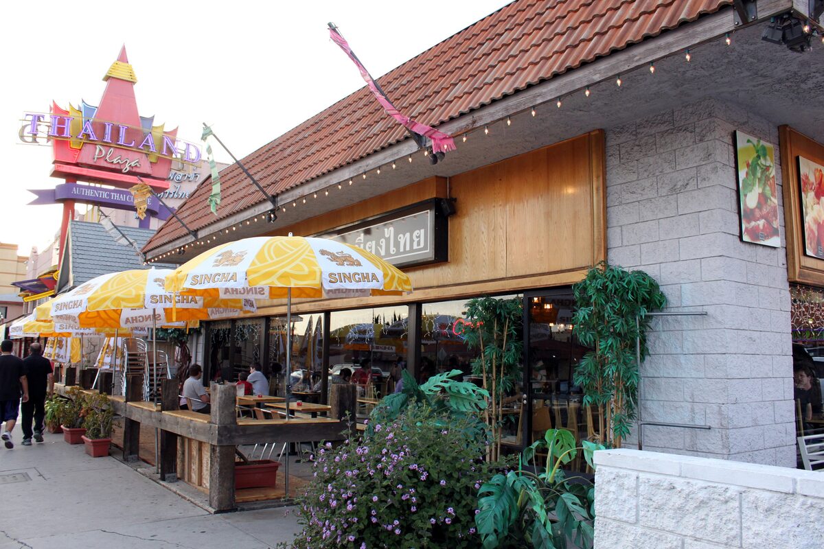 Thai restaurant terraces with yellow Singha umbrellas and a Thailand Plaza sign in Thai Town