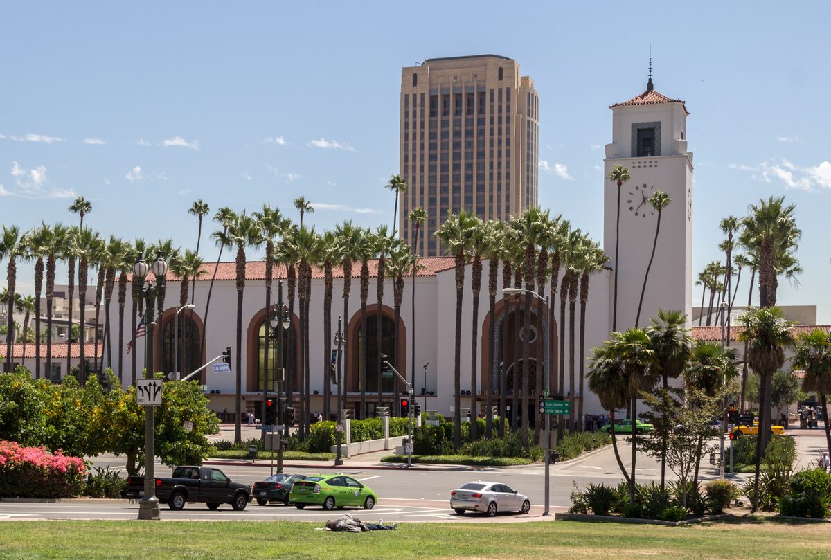 The long Mission Revival facade and clock tower of Los Angeles Union Station behind a row of palm trees