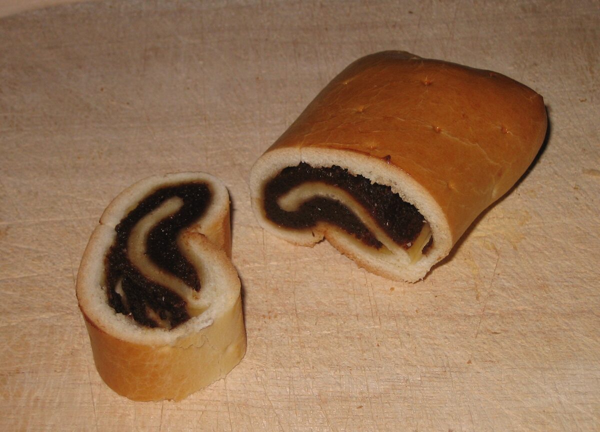 A sliced pear bread with its dark dried-fruit filling on a wooden board