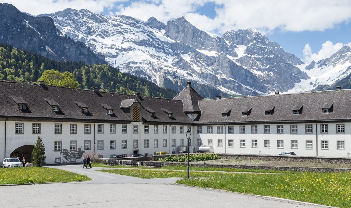 The long white Benedictine abbey of Engelberg below snowy peaks