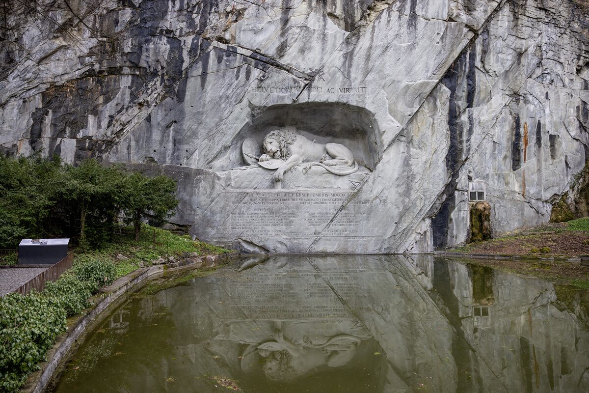 The Lion Monument carved into the rock face, with the still pool of water in front of it