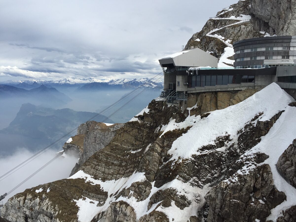 The Pilatus summit station built into the rock face, with snow on the slopes below