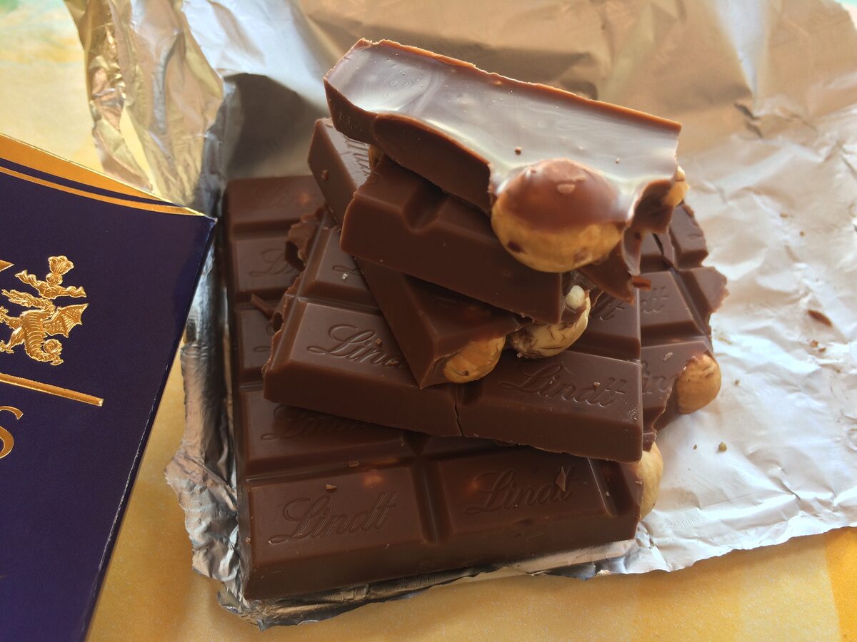Milk chocolate bars broken into pieces, one with hazelnuts, on silver foil