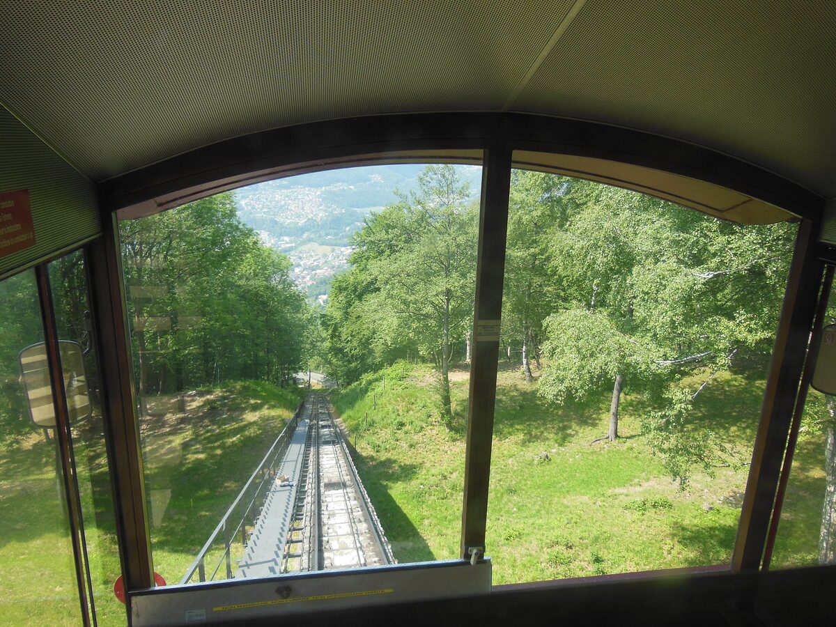 The view from inside a Monte Brè funicular car down the green track toward the valley