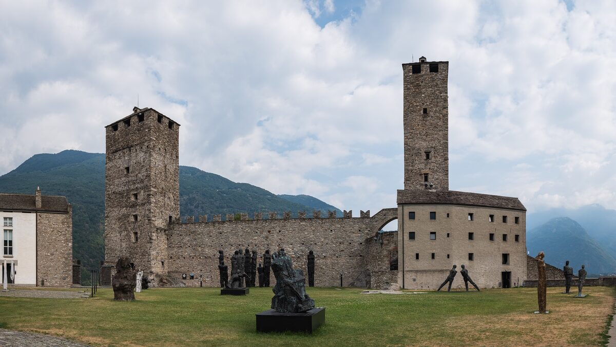 The twin towers of Castelgrande above the castle walls, with a sculpture on the grass in front
