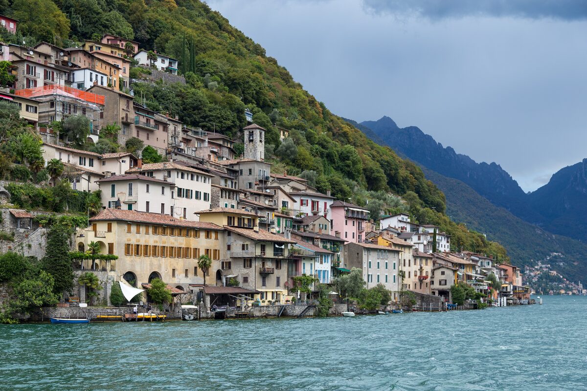The houses of Gandria stacked along the lakeshore below a steep wooded slope