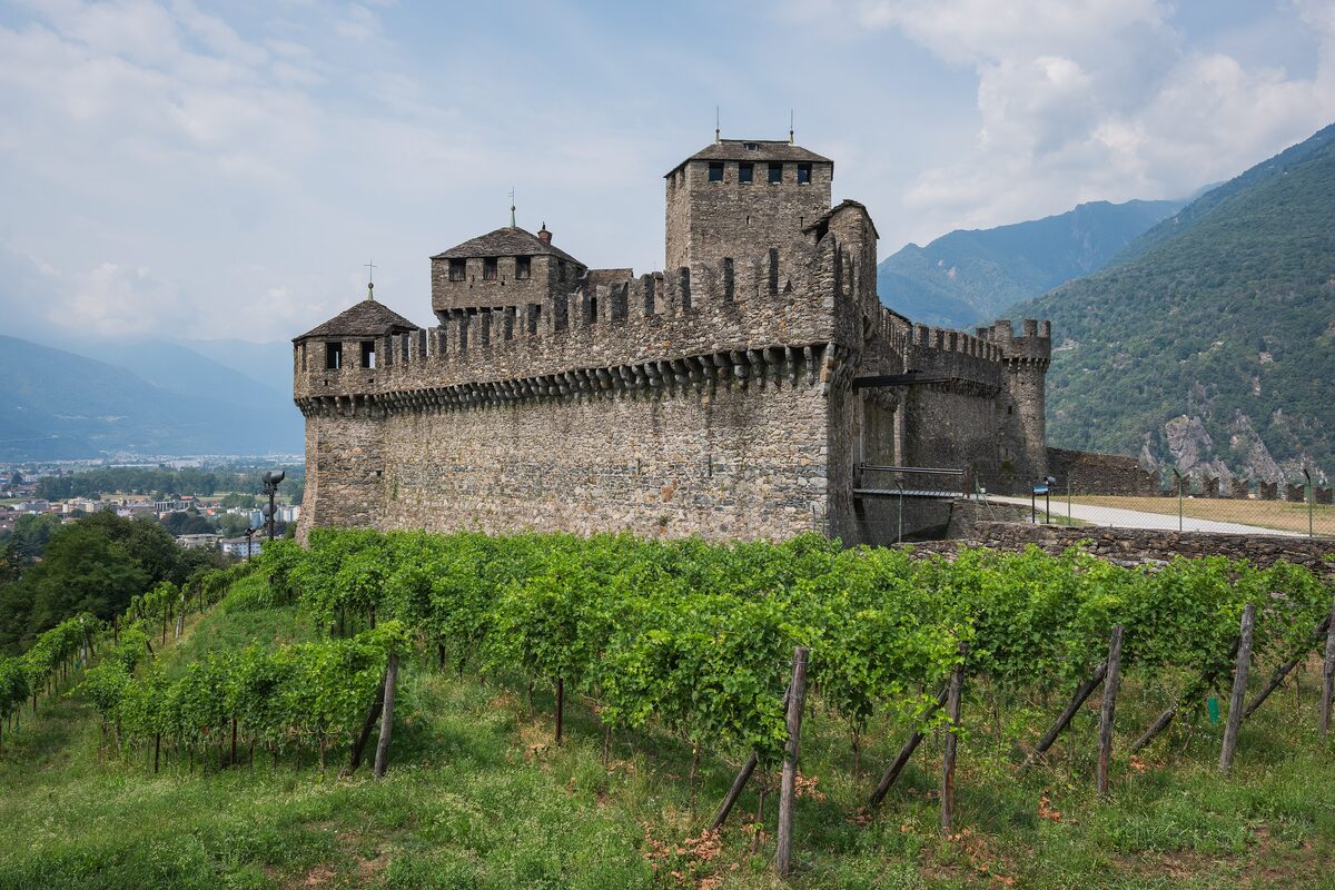 Castello di Montebello's stone walls and towers above rows of vines on the hillside