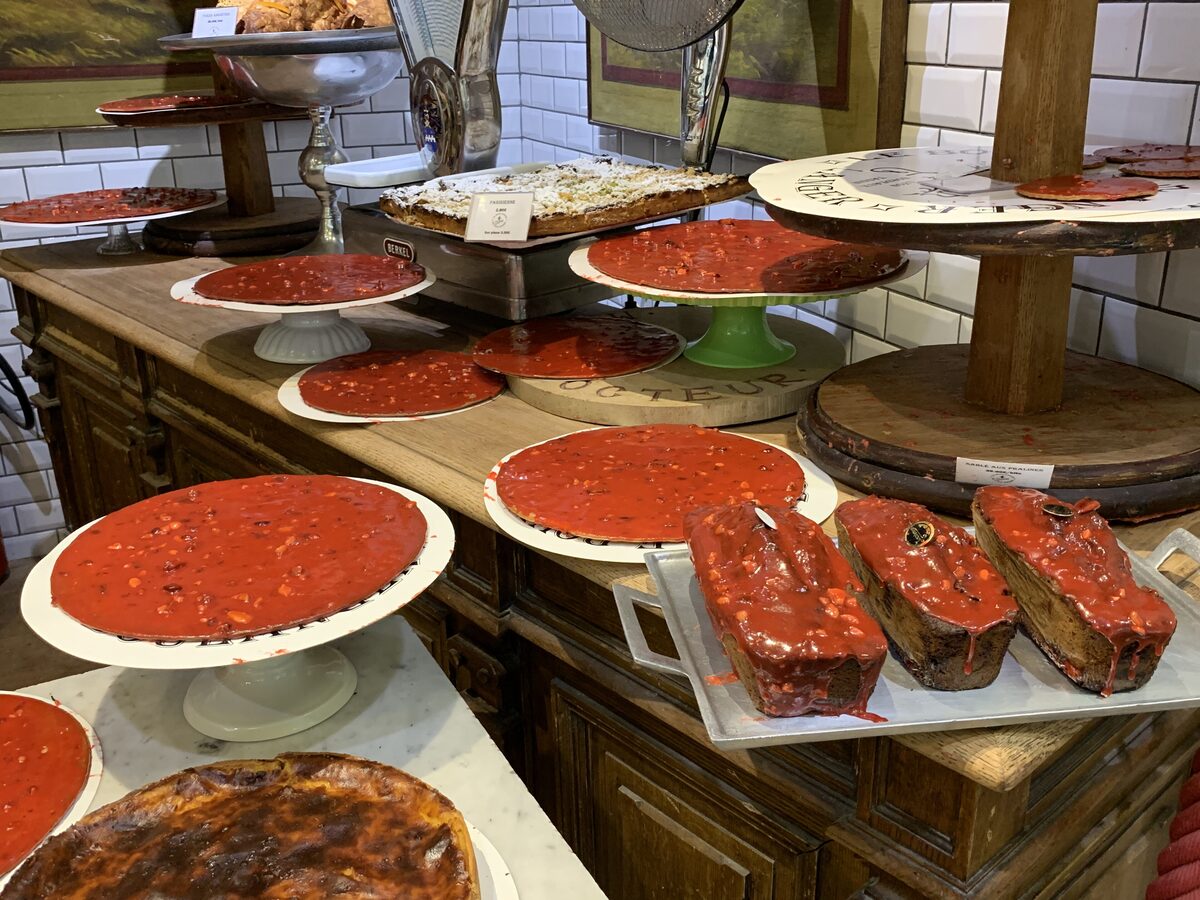 Bright pink praline tarts and praline brioche on stands in a Lyon pastry shop