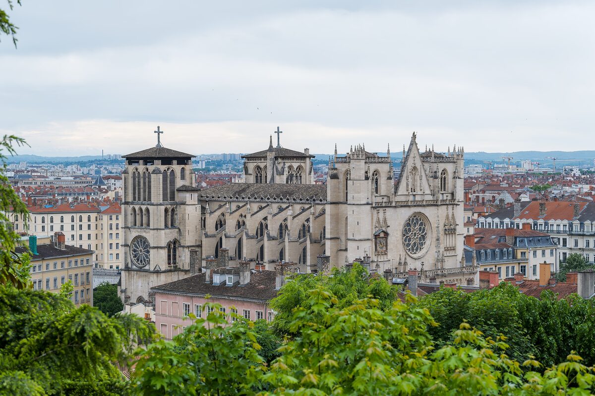 The Gothic facade and towers of Lyon's Cathédrale Saint-Jean seen from the hillside above, with the city spread out behind