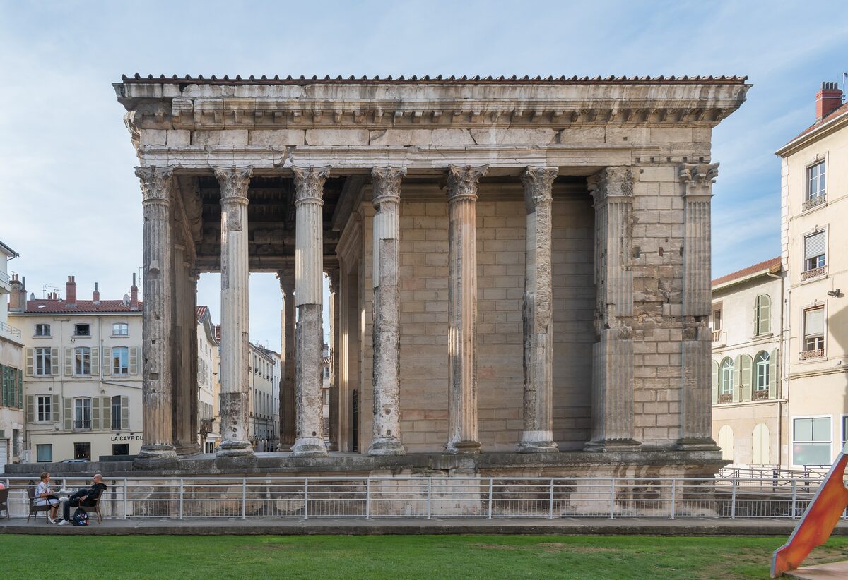 The Roman Temple of Augustus and Livia in Vienne, with its Corinthian columns, standing on a lawn in a town square