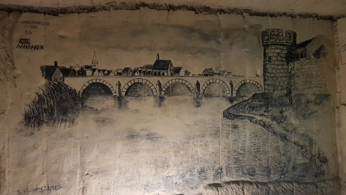 A charcoal drawing of Maastricht's old bridge and city wall sketched on the pale limestone wall of a cave tunnel