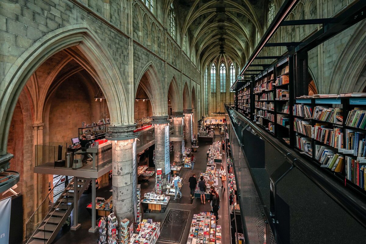 Bookshelves on a black steel structure rising inside the Gothic nave of the old Dominican church, with painted vaults and columns