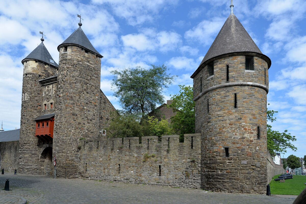 The Helpoort, a medieval stone gate with two round towers and pointed slate roofs, joined to a crenellated city wall