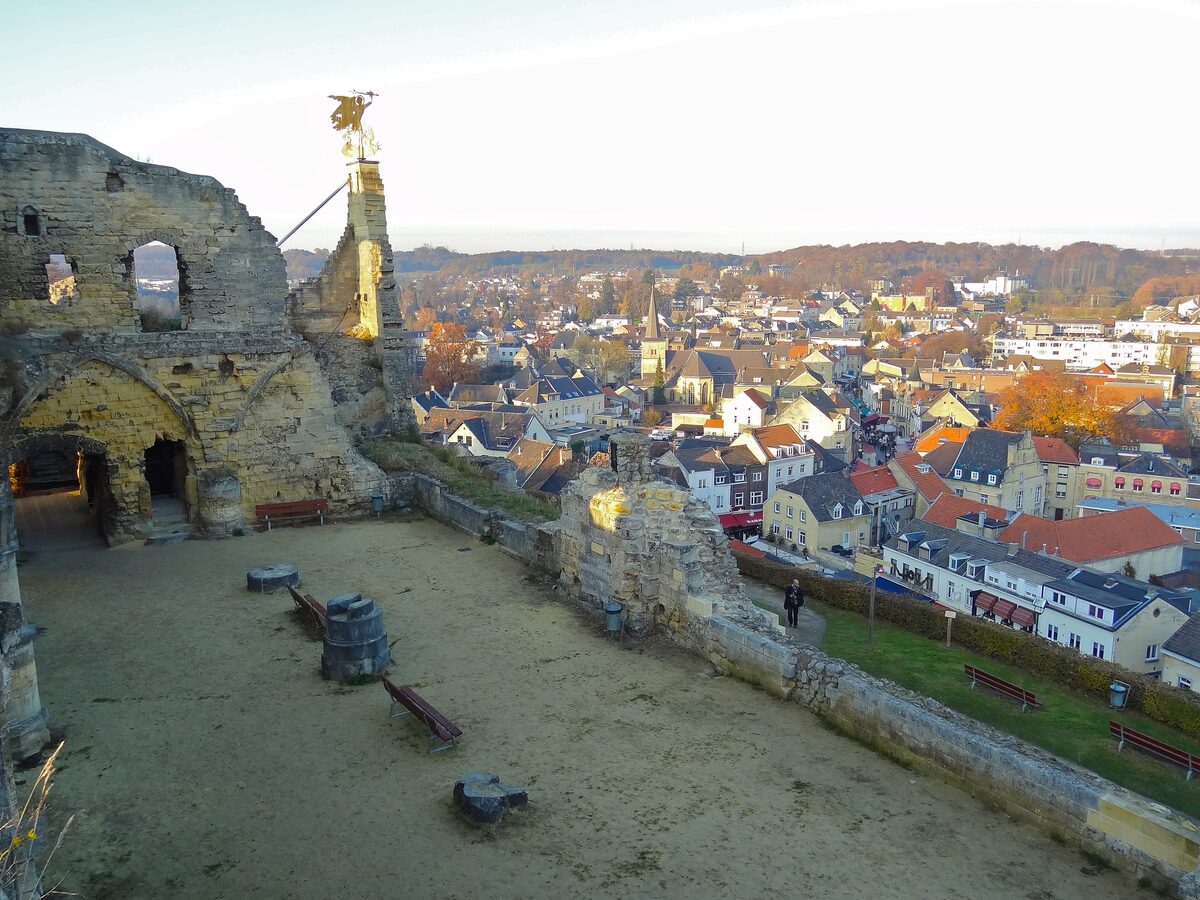 The ruined stone walls of Valkenburg Castle on its hill, with the roofs of Valkenburg and the green hills spread out below