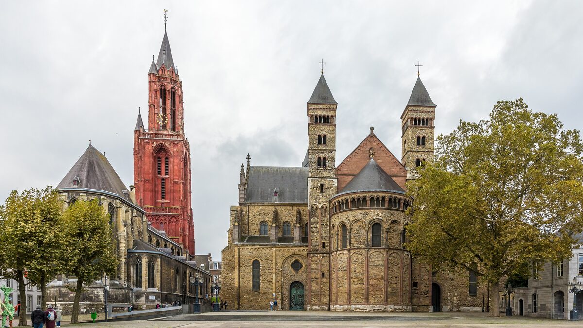 The red Gothic tower of Sint Janskerk next to the Romanesque Basilica of Saint Servatius with its towers and apse, on the edge of the Vrijthof