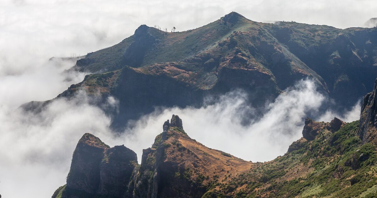 Rocky peaks of the central massif seen from Pico do Arieiro, rising out of a sea of cloud in bright daylight