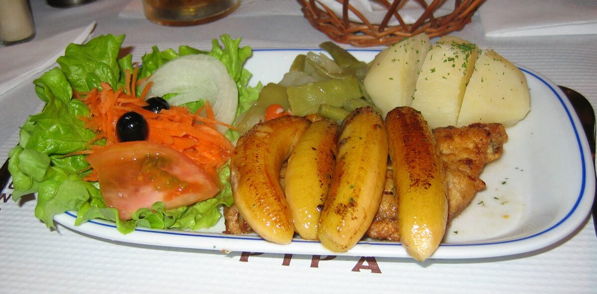 Grilled black scabbard fish with fried banana, potatoes and salad on a white plate