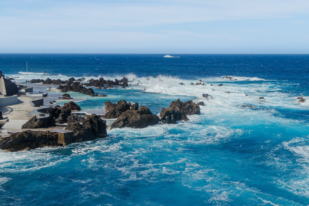 Ocean waves breaking over black lava rocks and the sea pools of Porto Moniz