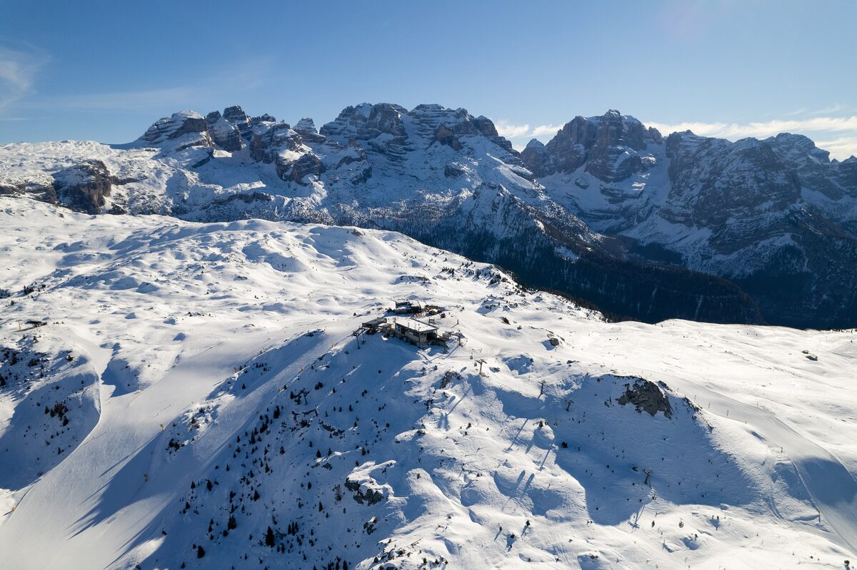 Snowy pistes and a mountain restaurant in the Madonna di Campiglio ski area, with the Brenta peaks behind