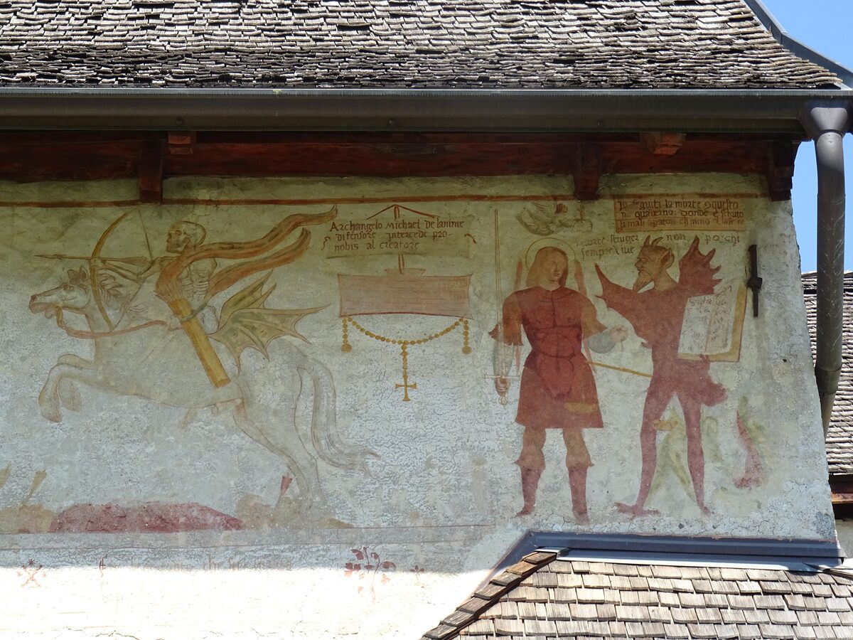 Outdoor fresco on the wall of San Vigilio church in Pinzolo, with figures from the danse macabre in red and ochre