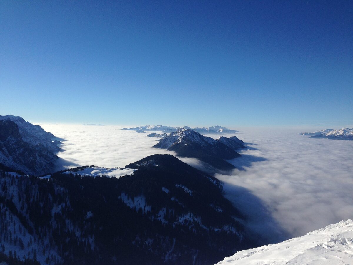 A sea of cloud filling the valley below the snowy ridge of the Doss del Sabion under a deep blue sky