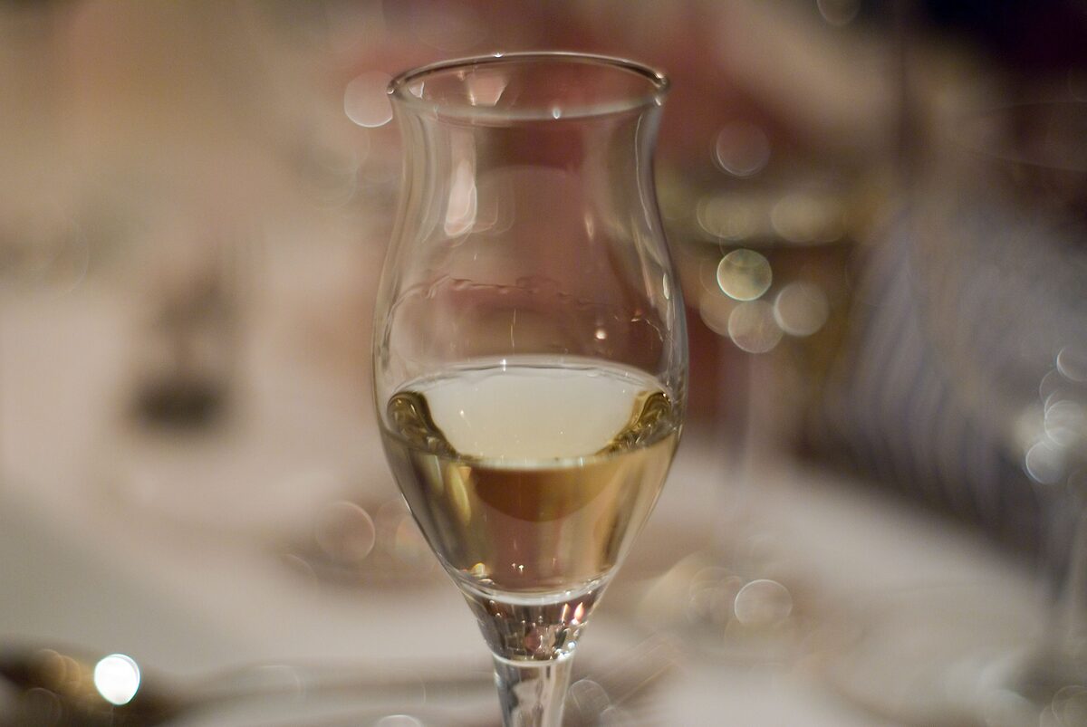 A tulip-shaped glass with a measure of clear grappa on a restaurant table