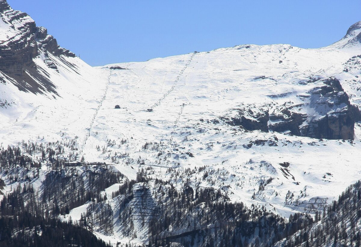 Snow-covered slopes on the Grostè side of the valley, with a line of lift cables climbing the mountain