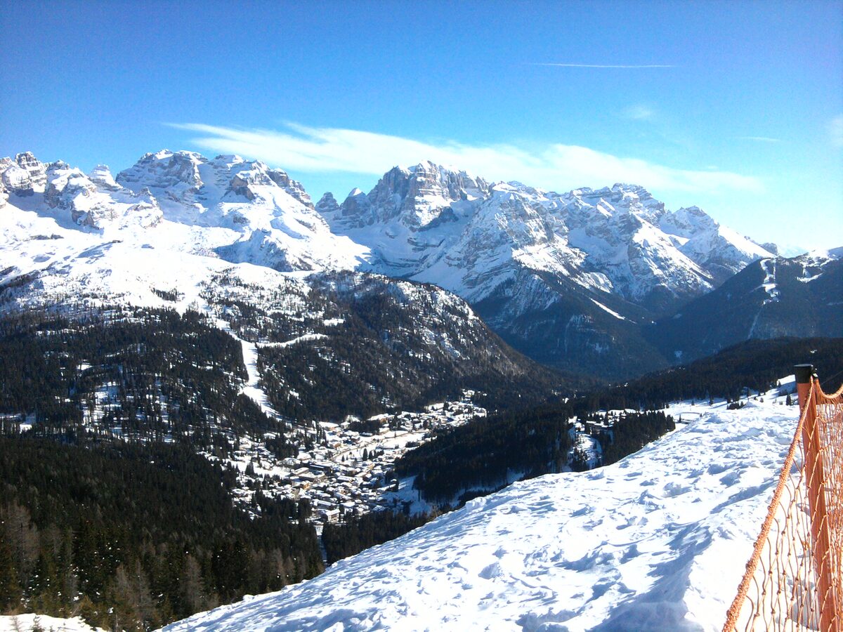 Looking down from a snowy ridge above Pradalago to Madonna di Campiglio in the valley, with the Brenta peaks opposite