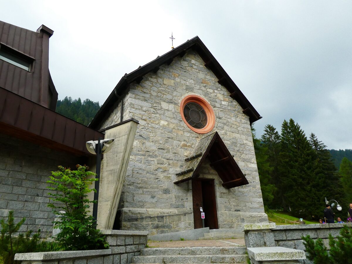 The small stone church of Santa Maria Antica with a round window and a steep roof, on a grey summer day