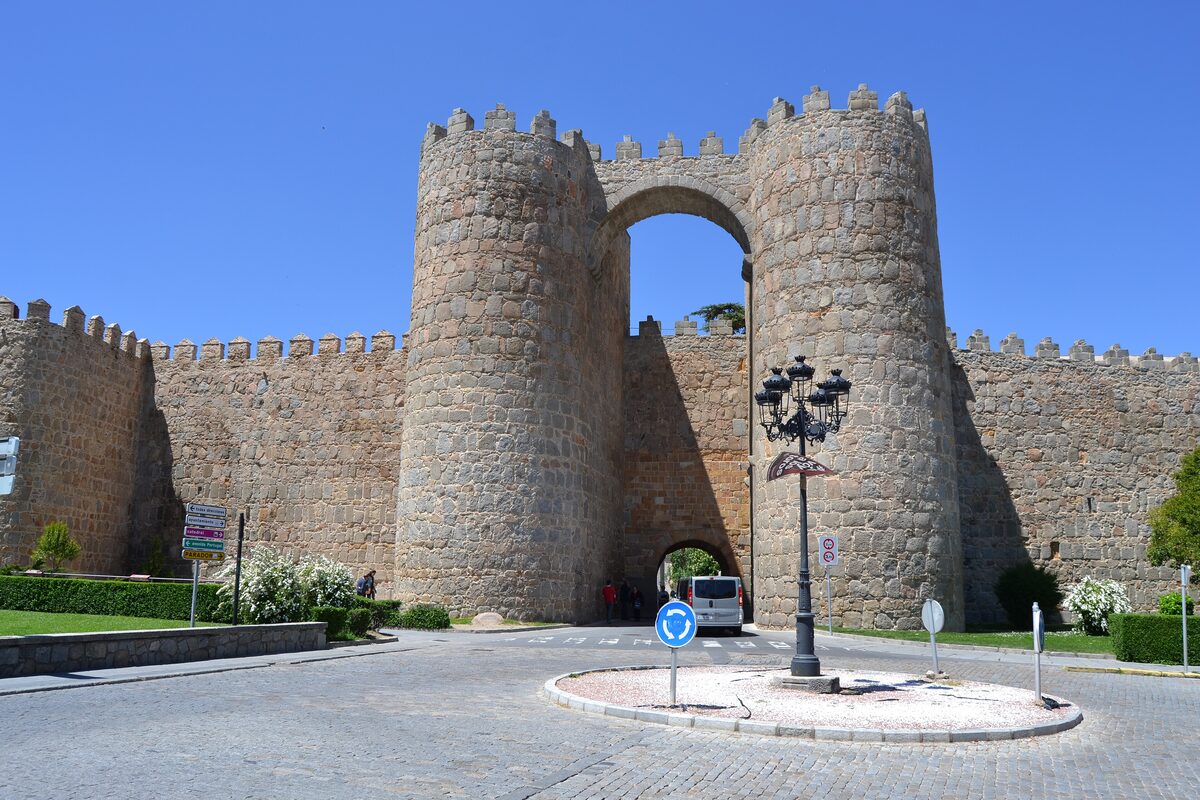 A gateway with twin round towers in Ávila's medieval city walls, with a roundabout in front