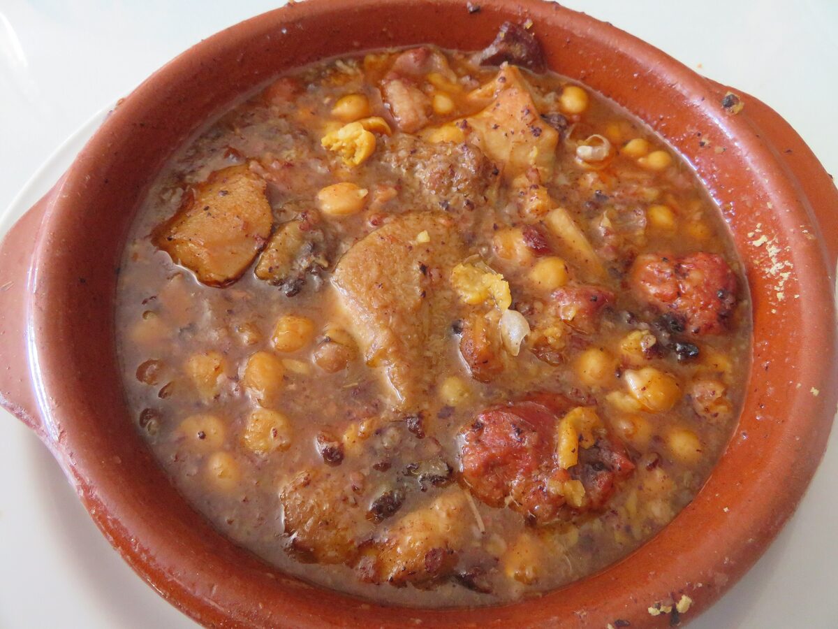 A clay pot of callos stew with chickpeas and pieces of tripe in a brown sauce