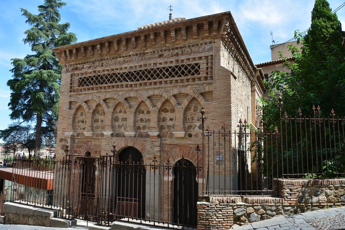 The small brick Mudéjar mosque of Cristo de la Luz with its patterned arches, behind an iron fence