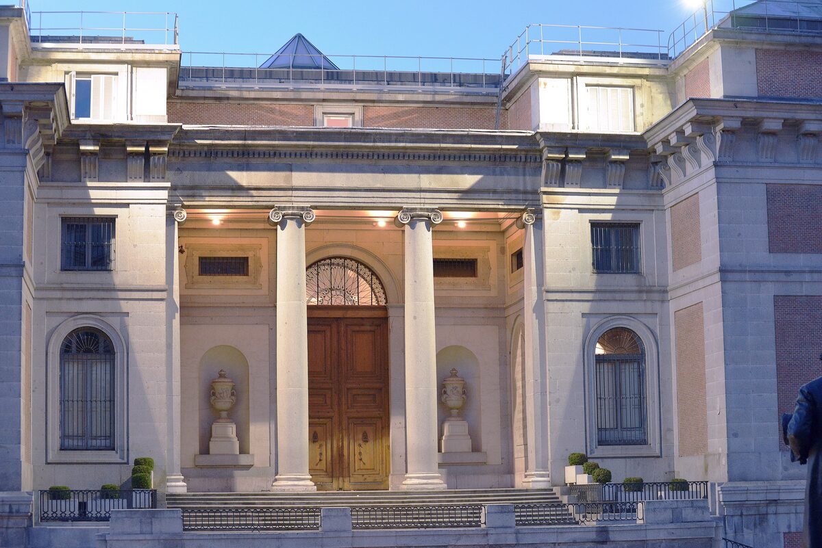 The Prado's north entrance with its Ionic columns and wooden doors, lit in the early morning